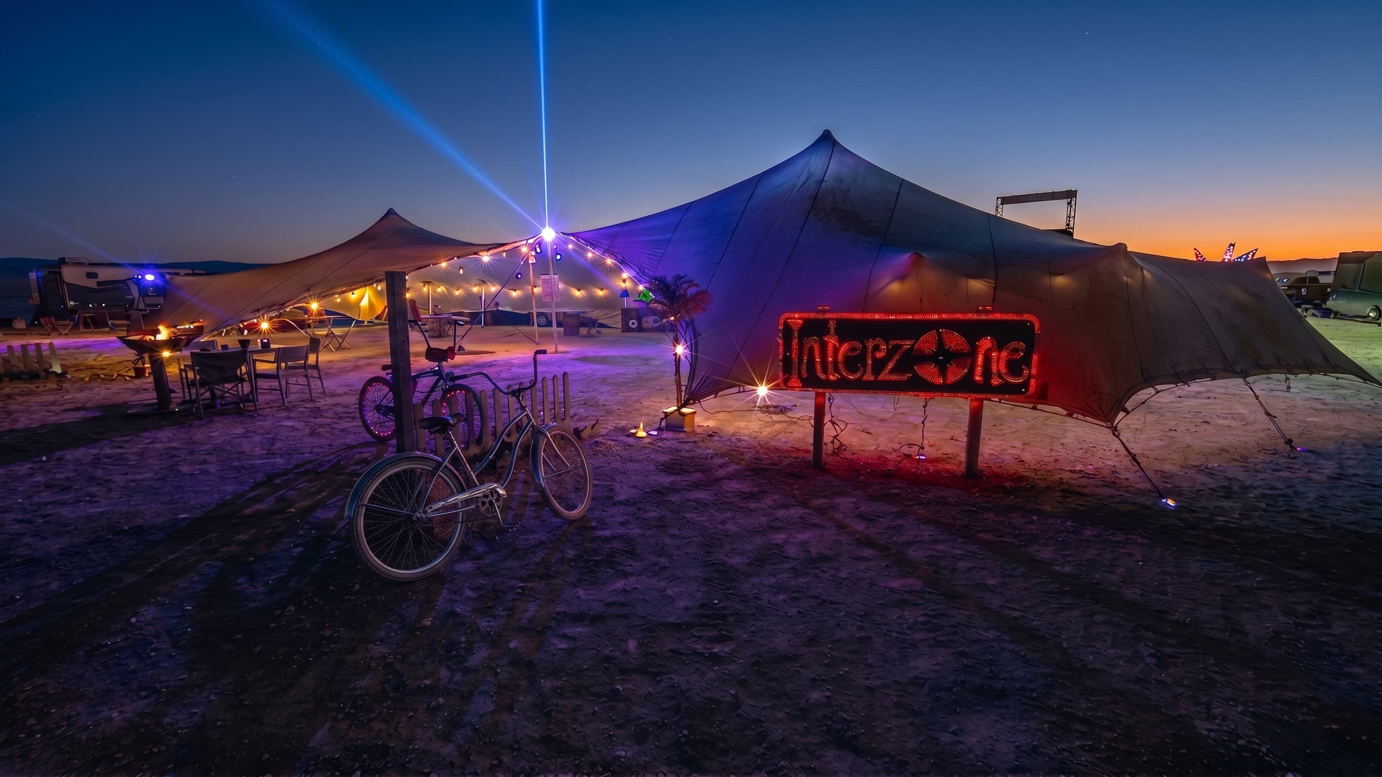 Camp Interzone at night — the stretch tent under the neon sign